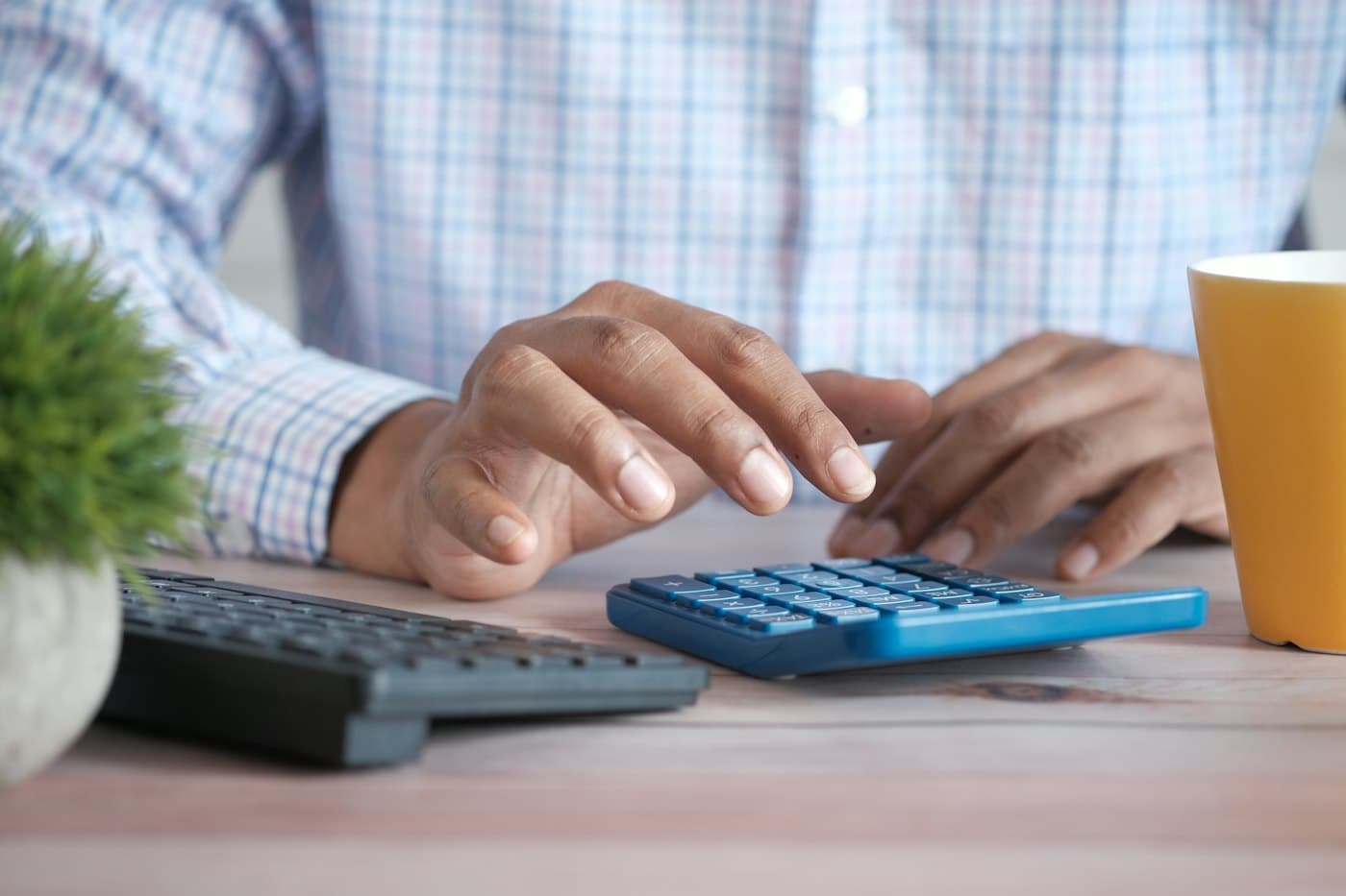 Des mains utilisant une calculatrice sur un bureau, pour estimer un budget