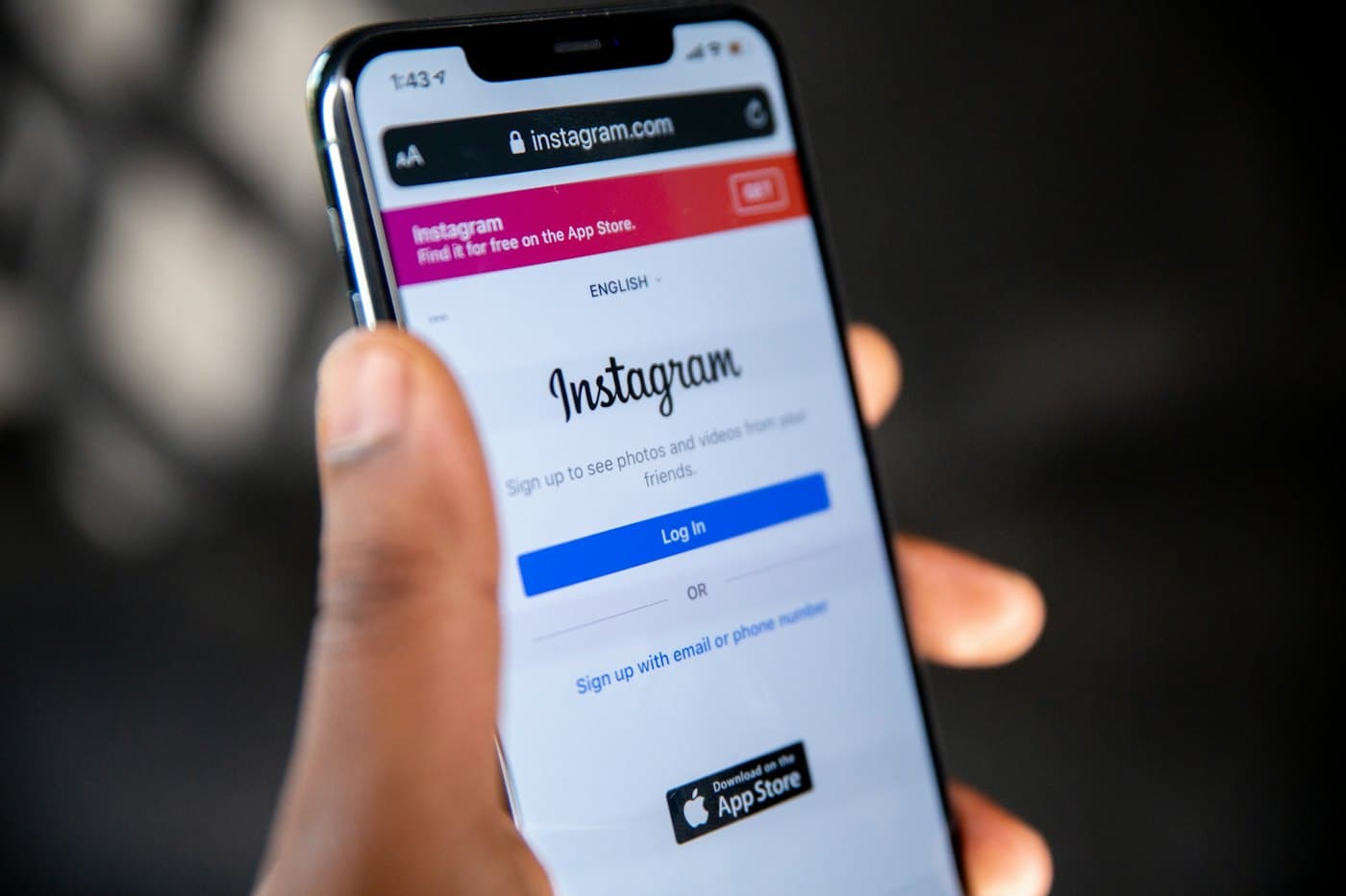 Une main tenant un smartphone ouvert sur la page de connexion Instagram