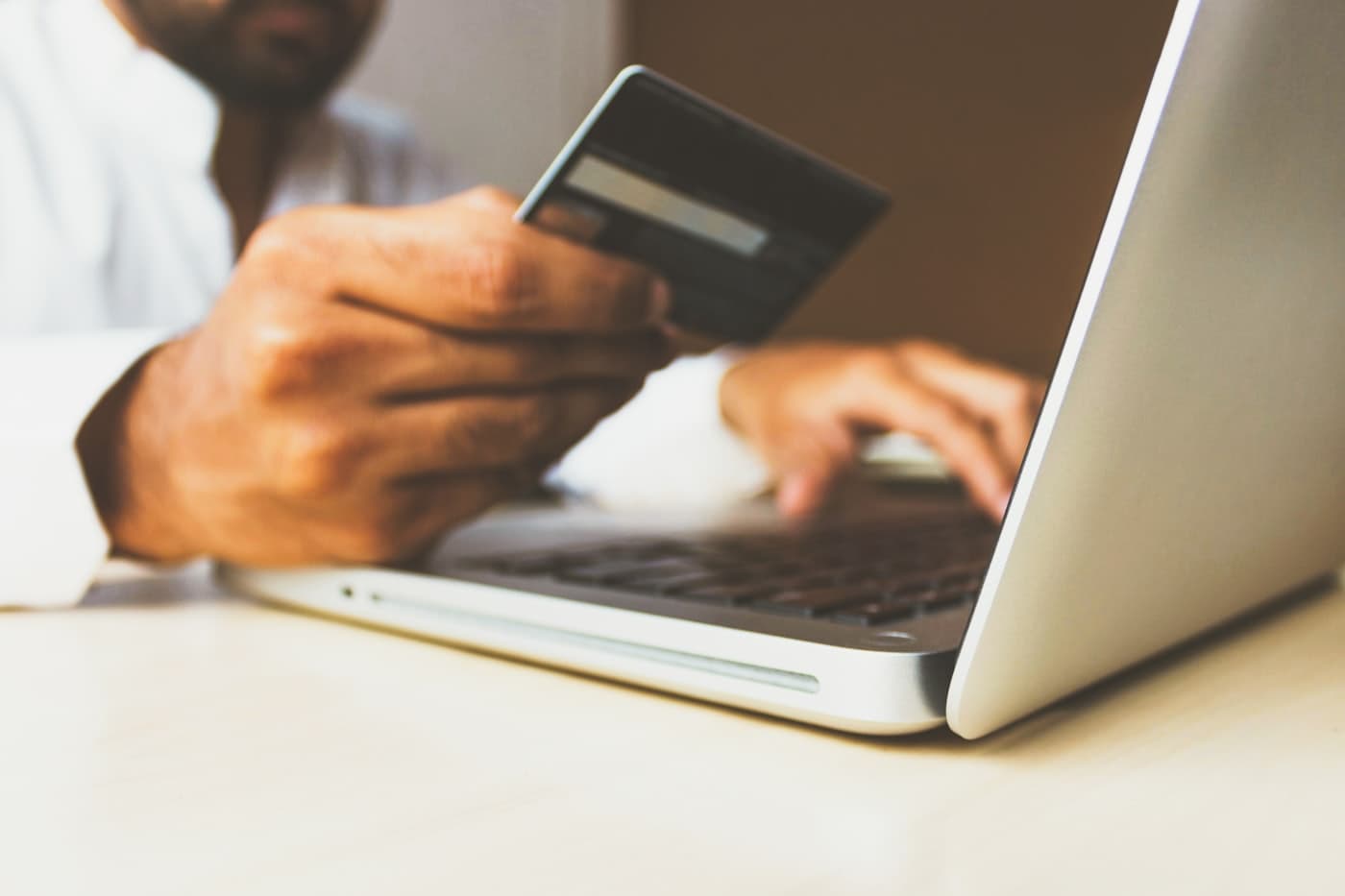 Une personne tenant une carte bancaire devant son ordinateur portable pour payer en ligne